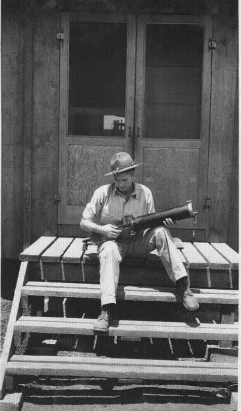 Photo of WW2 Veteran, David Shepherd, holding gun on barracks during war.